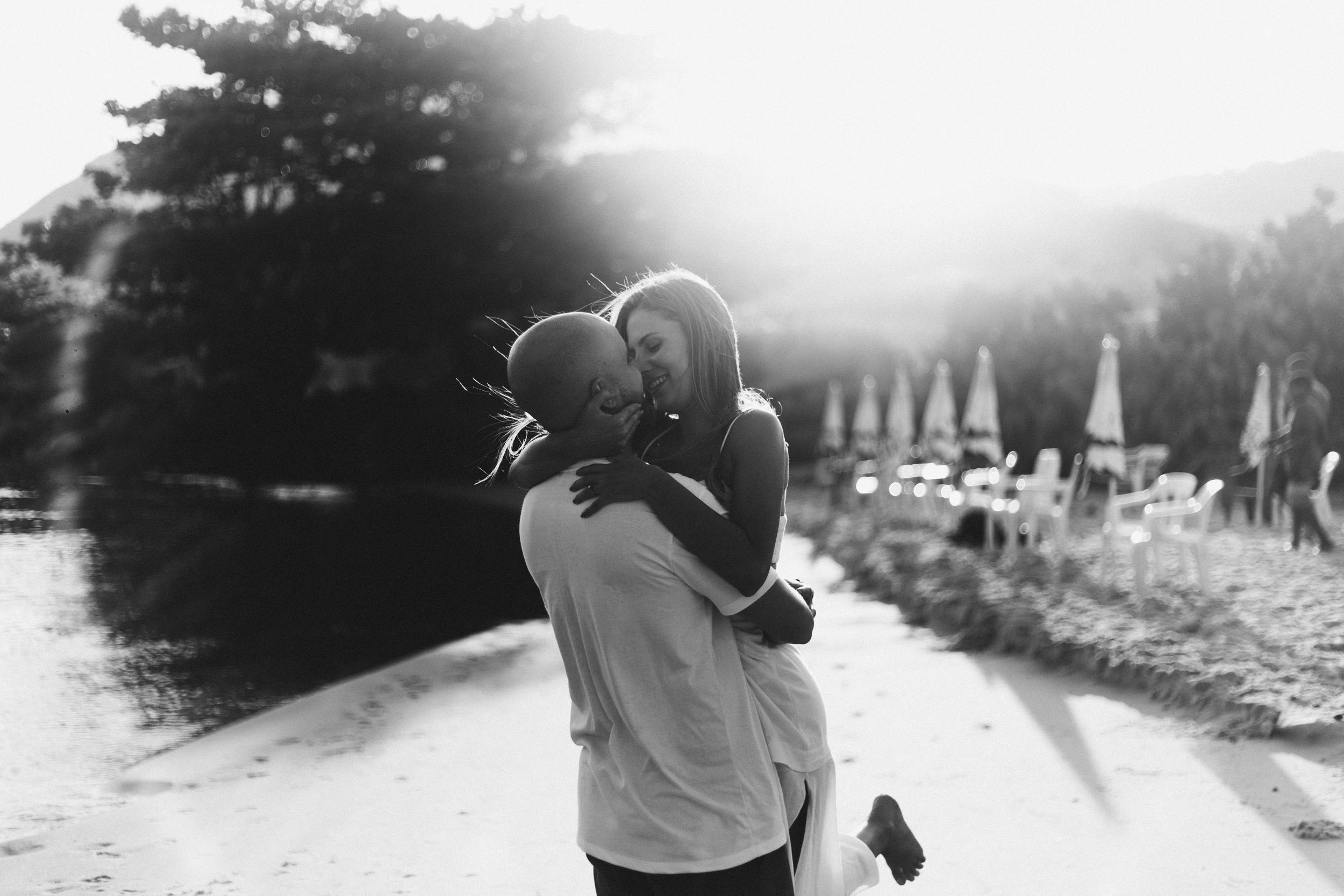 Black and white photo of a happy couple embracing on a sunny beach.